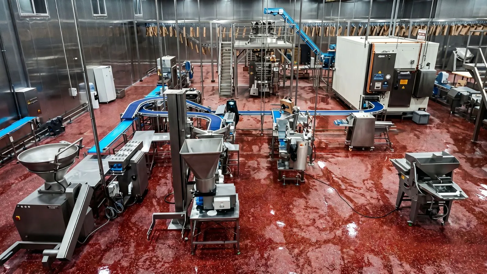 Blick von oben in eine Lebensmittelproduktion mit Förderbändern, Abfüllstationen und Verpackungsanlage